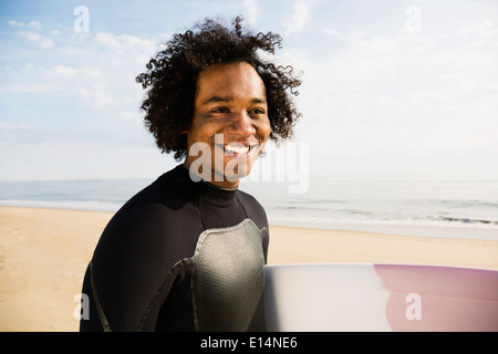 Gemischte Rassen Surfer tragen Board am Strand Stockfoto