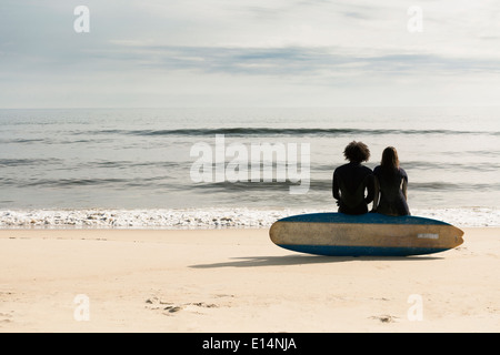 Surfer am Strand an Bord sitzen Stockfoto