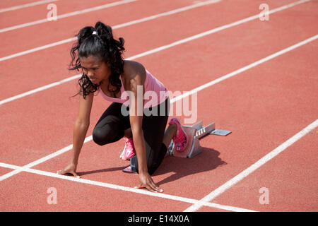 Sportliche junge Frau in Ausgangsposition in Startlöchern, Laufstrecke Stockfoto