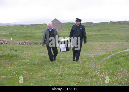 Vorsitzender Offizier Hugh O'Donnell und Garda Officer p.j. McHugh tragen die Wahlurne auf der Insel Innishfree, County Donegal, Stockfoto