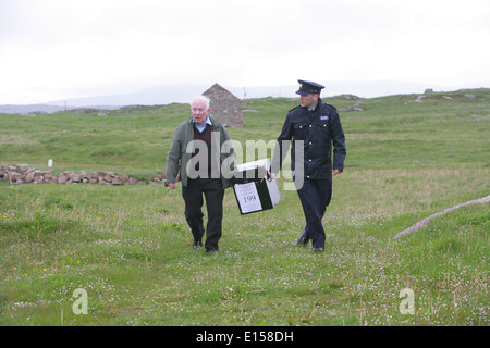 Vorsitzender Offizier Hugh O'Donnell und Garda Officer p.j. McHugh tragen die Wahlurne auf der Insel Innishfree, County Donegal, Stockfoto