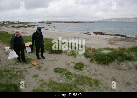 Vorsitzender Offizier Hugh O'Donnell und Garda Officer p.j. McHugh tragen die Wahlurne auf der Insel Innishfree, County Donegal, Stockfoto