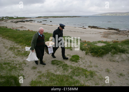 Vorsitzender Offizier Hugh O'Donnell und Garda Officer p.j. McHugh tragen die Wahlurne auf der Insel Innishfree, County Donegal, Stockfoto