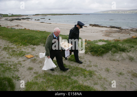 Vorsitzender Offizier Hugh O'Donnell und Garda Officer p.j. McHugh tragen die Wahlurne auf der Insel Innishfree, County Donegal, Stockfoto