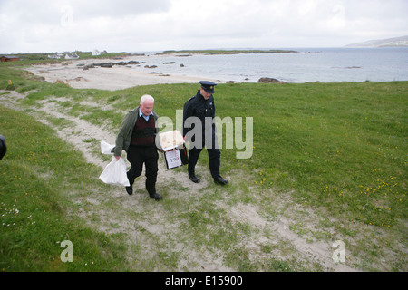 Vorsitzender Offizier Hugh O'Donnell und Garda Officer p.j. McHugh tragen die Wahlurne auf der Insel Innishfree, County Donegal, Stockfoto