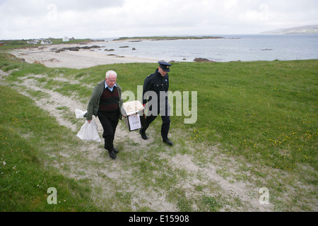 Vorsitzender Offizier Hugh O'Donnell und Garda Officer p.j. McHugh tragen die Wahlurne auf der Insel Innishfree, County Donegal, Stockfoto