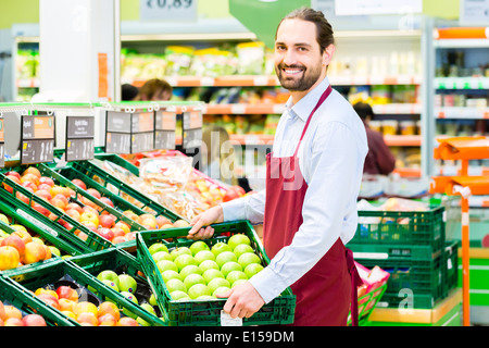 Supermarkt-Sachbearbeiter füllt sich Apple Lagerregale in Obst-Abteilung Stockfoto