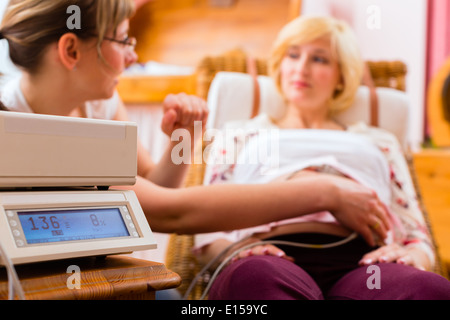 Hebamme Exanimating Bauch der Schwangeren mit CTG Scannen in der Praxis Stockfoto