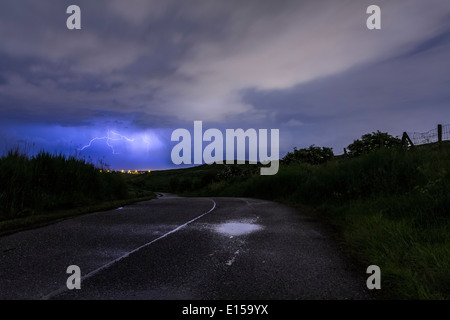 Eine Straße führt zu einem Sturm tobt hinter den Hügeln. Stockfoto