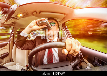 Betrunkener Mann in einem Anzug und Sonnenbrille fahren auf einer Straße im Auto Fahrzeug. Stockfoto