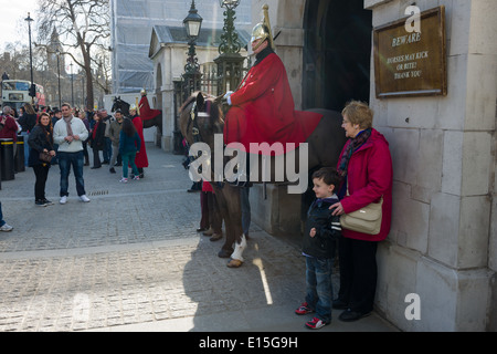 Frau und Kind posiert neben montierten Mitglied der Household Cavalry, Life Guards Regiment, Horse Guards Parade, London, England Stockfoto