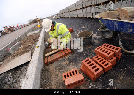 Handwerker Handwerker auf einem Gebäude site Ziegel eine Entwässerung-Abschnitt auf einer Straße herumliegen. Stockfoto