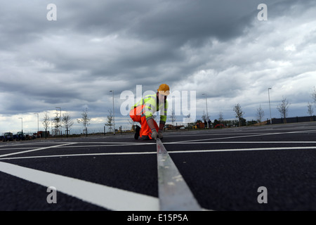 Handwerker Handwerker Malerei Parkplatz Bucht weiße Linien auf einem Parkplatz auf einer Baustelle. Stockfoto