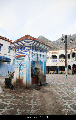 Mann trinkt aus einem Wasserbrunnen in Chefchaouen, Marokko Stockfoto