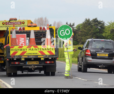 Bauarbeiter mit Lollipop Stop - Go Zeichen zur Steuerung von Datenverkehr auf Baustellen Vereinigtes Königreich Stockfoto