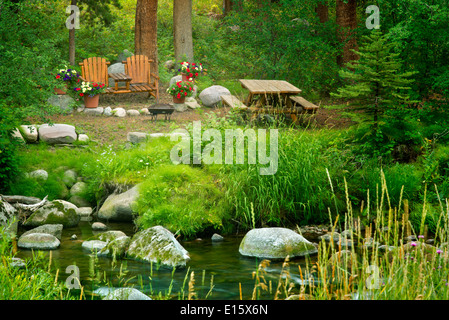 Picknickplatz mit Tisch Stühlen und Blumen auf Gore Creek. Vail, Colorado Stockfoto