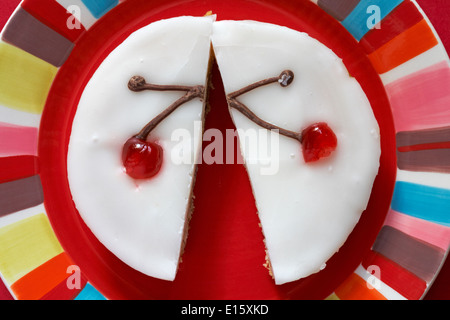 Cherry Bakewell tart in der Hälfte auf Rot bunte Platte - von oben nach unten suchen. Stockfoto