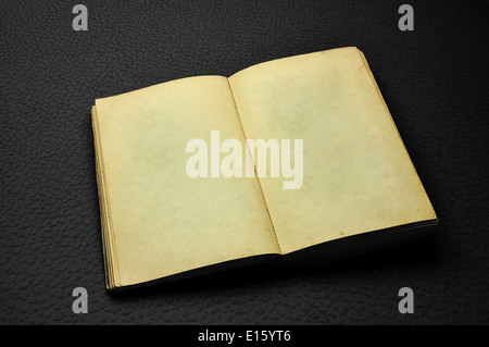 Alten geöffnete leere Buch auf dunklen schwarzen Kunstleder-Hintergrund Stockfoto