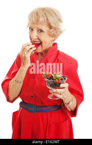 Ziemlich senior Frau essen eine Schale mit gesunden leckeren gemischten Beeren. Isoliert auf weiss. Stockfoto