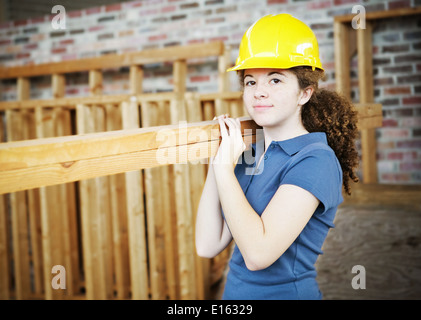 Junge weibliche Lehrling tragen Bretter auf einer Baustelle. Stockfoto