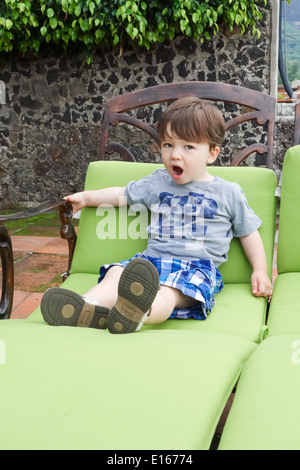 Junge sitzt auf einem Liegestuhl und Gähnen Stockfoto