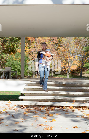 Frau trägt ihr Baby Boy und bewegt sich in einem park Stockfoto