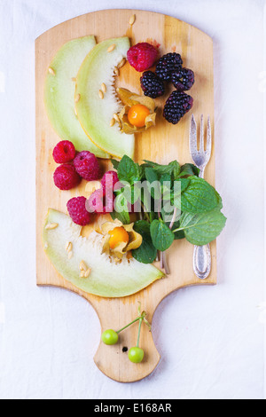 Beeren, Minze und Melone auf Holzbrett Stockfoto