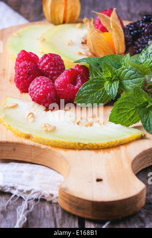 Beeren, Minze und Melone auf Holzbrett Stockfoto