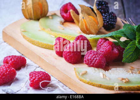 Beeren, Minze und Melone auf Holzbrett Stockfoto