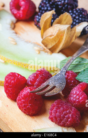 Beeren, Minze und Melone auf Holzbrett Stockfoto