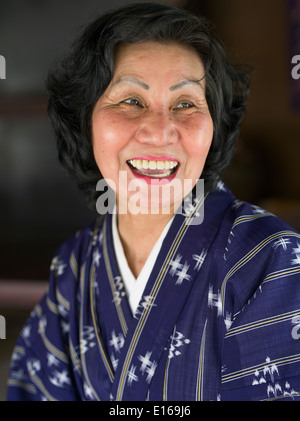 Schöne ältere Okinawan Frau tragen Yukuata und Lächeln auf den Lippen. Ryukyu Mura, Okinawa, Japan Stockfoto