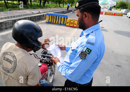 Islamabad, Pakistan. 24. Mai 2014. Ein pakistanischer Polizist prüft Dokumente ein Motorradfahrer an einem Checkpoint aufgrund hoher Sicherheitswarnung in Islamabad, der Hauptstadt von Pakistan, am 24. Mai 2014. Ein Wachmann wurde getötet und einen anderen verletzt, wenn zwei separate Bombenanschläge der pakistanischen Hauptstadt Islamabad in den frühen Morgenstunden des Samstag morgens getroffen, sagten Beamte. Bildnachweis: Ahmad Kamal/Xinhua/Alamy Live-Nachrichten Stockfoto