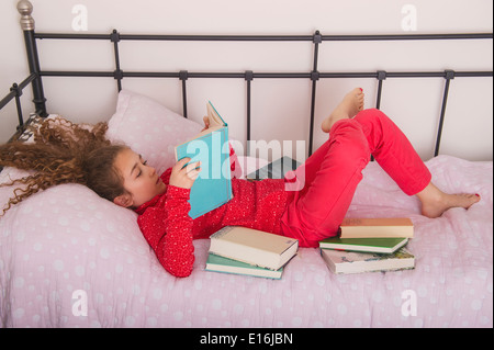 Mädchen (10-12) Lesebuch auf Bett, Milano, Italien Stockfoto