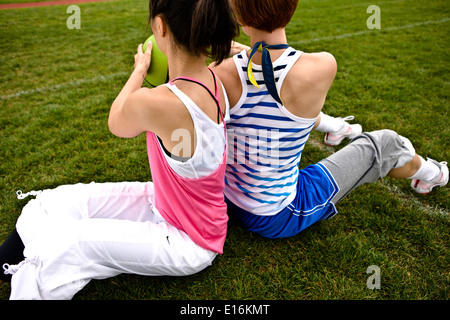 Freundinnen sitzen auf Rasen Stockfoto