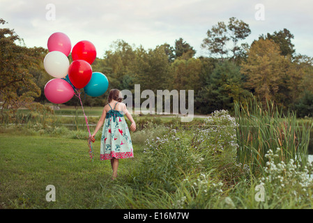 Mädchen (8-9) zu Fuß mit Luftballons Stockfoto