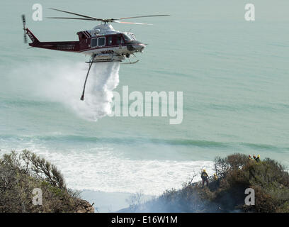 San Onofre, Kalifornien, USA. 14. Mai 2014. Eine Orange County Fire Authority Wasser fallen Bell UH-1 Super Huey Hubschrauber kämpft das Pendleton West Autobahn Feuer im San Onofre State Park in Kalifornien auf Mittwoch, 14. Mai 2014. Eine Camp Pendleton Marine Base Feuer kämpfen Hand Besatzung stehen als die OCFA Hubschrauber Aids in das Feuer im Blick auf den Pazifischen Ozean am Mittwoch Nachmittag aufwischen. © David Bro/ZUMAPRESS.com/Alamy Live-Nachrichten Stockfoto