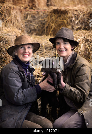 Zwei Bäuerinnen mit einem Neugeborenen Frühlingslamm aus ihrer Manx Loaghtan Herde von Schafen Wiltshire UK Stockfoto