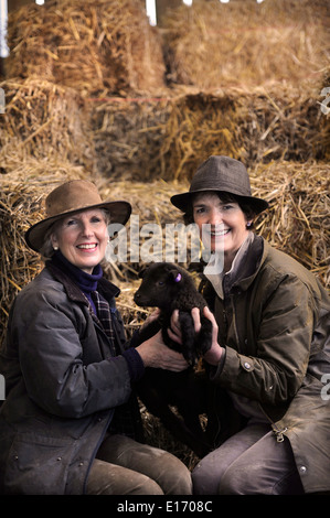Zwei Bäuerinnen mit einem Neugeborenen Frühlingslamm aus ihrer Manx Loaghtan Herde von Schafen Wiltshire UK Stockfoto