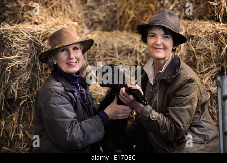 Zwei Bäuerinnen mit einem Neugeborenen Frühlingslamm aus ihrer Manx Loaghtan Herde von Schafen Wiltshire UK Stockfoto