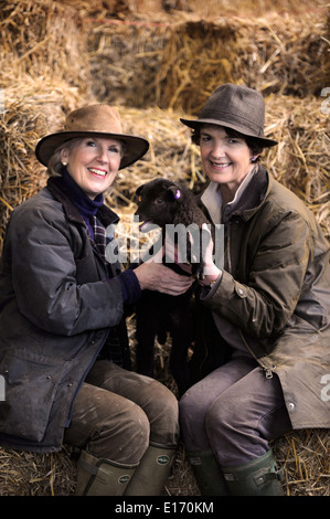 Zwei Bäuerinnen mit einem Neugeborenen Frühlingslamm aus ihrer Manx Loaghtan Herde von Schafen Wiltshire UK Stockfoto
