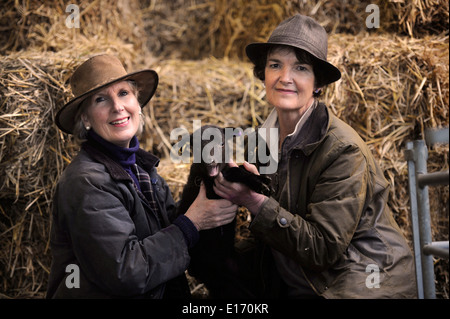 Zwei Bäuerinnen mit einem Neugeborenen Frühlingslamm aus ihrer Manx Loaghtan Herde von Schafen Wiltshire UK Stockfoto