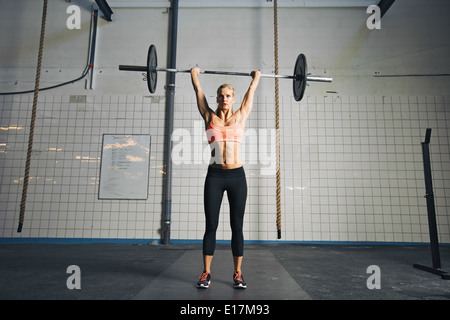 Voller Länge Bild der starke junge Frau mit Langhantel und Gewicht Platten Overhead Crossfit Übung zu tun. Fit-Sportlerin. Stockfoto