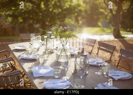 Bouquet und Gedecke auf ruhigen Terrassentisch Stockfoto