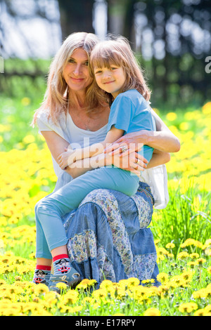 Junge umarmt seine Mutter sitzt auf dem Schoß im Garten Stockfoto