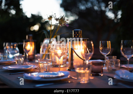 Kerzen in den Laternen auf Terrasse Esstisch mit Maßgedecke Stockfoto