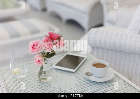 Rosa Rosen auf Terrassentisch mit Kaffeetasse und digital-Tablette Stockfoto