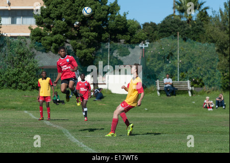 Junior-Football-Spieler springt in die Luft in Richtung den Ball, Cape Town, Südafrika Stockfoto