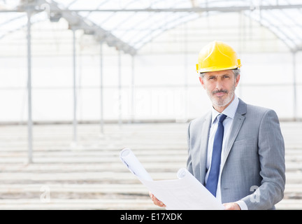 Porträt des überzeugt Architekten mit Blaupause im Gewächshaus Stockfoto