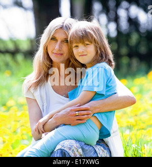 Junge umarmt seine Mutter sitzt auf dem Schoß im Garten Stockfoto