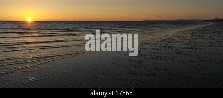 Blick auf orangefarbenen Himmel Sonnenuntergang über irische See von nassen Sand plätschert St Annes Beach Blackpool hin Cumbrian Mountains Stockfoto